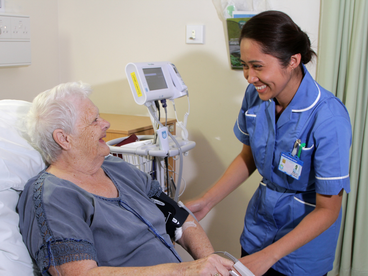 A smiling nurse at a patient's bedside